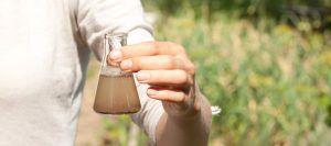 Researcher holds murky water test beaker in the field